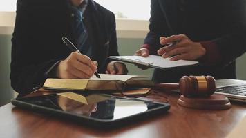 Business and lawyers discussing contract papers with brass scale on desk in office. Law, legal services, advice, justice and law concept picture with film grain effect video