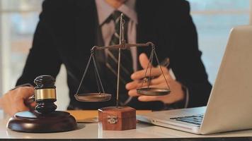 Business and lawyers discussing contract papers with brass scale on desk in office. Law, legal services, advice, justice and law concept picture with film grain effect video