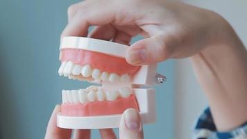 concepto de estomatología, retrato parcial de una chica con fuertes dientes blancos mirando la cámara y sonriendo, con los dedos cerca de la cara. primer plano, de, mujer joven, en, dentista, estudio, adentro video