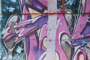 Fragment of graffiti drawings. The old wall decorated with paint stains in the style of street art culture. Colored background texture in purple tones photo