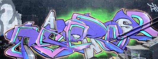 Fragment of graffiti drawings. The old wall decorated with paint stains in the style of street art culture. Colored background texture in purple tones photo