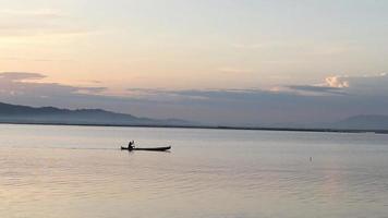 silueta de pescadores disfrutando de una hermosa puesta de sol en su bote mientras pescan