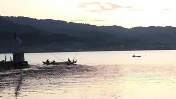 silhuett av fiskare njuter en skön solnedgång i deras båt medan fiske video