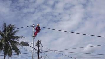 Gorontalo-Indonesia, December 2022 - Technicians connect cables to electric poles. Employee hanging by belt on electricity pole for laying low voltage cable video