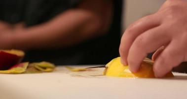 chef snijden een rijp mango voor sushi broodjes gebruik makend van een keuken mes in een hakken bord. -dichtbij omhoog schot video