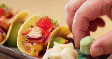 agregando wasabi a un plato de tacos preparados cubiertos con caviar en un restaurante de sushi - cerrar video