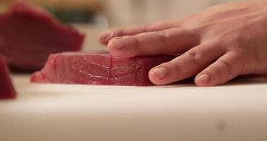 Küchenchef schneidet mit einem scharfen Messer ein frisches Thunfischfilet auf einem Schneidebrett. japanisches Restaurant. - Nahaufnahme video