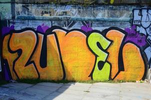 Fragment of graffiti drawings. The old wall decorated with paint stains in the style of street art culture. Colored background texture in warm tones photo