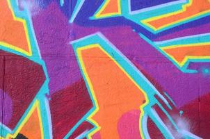 Fragment of graffiti drawings. The old wall decorated with paint stains in the style of street art culture. Colored background texture in purple tones photo