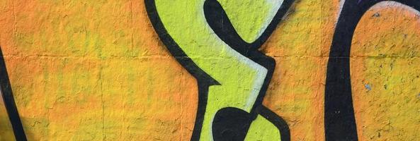 Fragment of graffiti drawings. The old wall decorated with paint stains in the style of street art culture. Colored background texture in warm tones photo