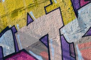 Fragment of graffiti drawings. The old wall decorated with paint stains in the style of street art culture. Colored background texture in warm tones photo