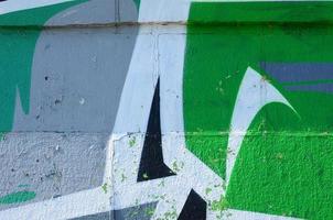 Fragment of graffiti drawings. The old wall decorated with paint stains in the style of street art culture. Colored background texture in green tones photo