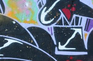 Fragment of graffiti drawings. The old wall decorated with paint stains in the style of street art culture. Colored background texture photo