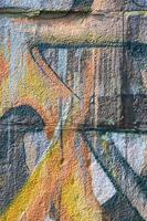 Fragment of graffiti drawings. The old wall decorated with paint stains in the style of street art culture. Colored background texture in warm tones photo