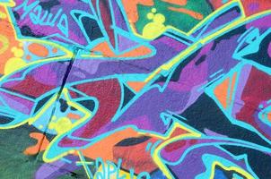 Fragment of graffiti drawings. The old wall decorated with paint stains in the style of street art culture. Multicolored background texture photo