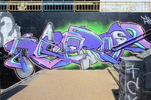 fragmento de dibujos de graffiti. la antigua muralla decorada con manchas de pintura al estilo de la cultura del arte callejero. textura de fondo coloreada en tonos morados foto