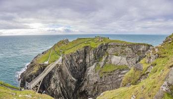 Pedastrian bridge to Mizen Head lighthouse in southern west Ireland during daytime photo