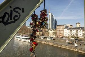 Love locks on bridge Eiserner Steg in Frankfurt with skyline and Main river in background photo