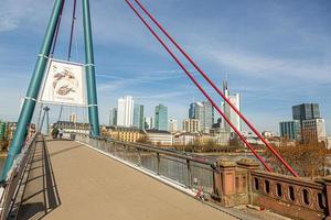 imagen del puente peatonal holbeinsteg en frankfurt sobre el río principal y el horizonte bajo el cielo azul y el sol foto