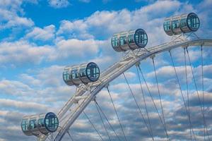 Detail view of gondolas of Ferris wheel against cloudy sky photo