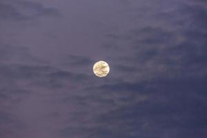 Image of full moon against colorful evening sky with light clouds photo