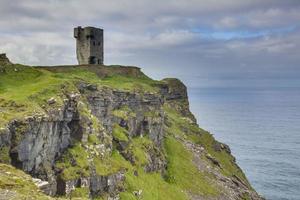 Tower ruin over steeply cliffs at Irish West coast during daytime photo