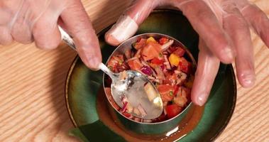 plato de comida - chef con guantes sosteniendo una cuchara y presionando el ceviche de atún en un plato de cerámica. - tiro de ángulo alto