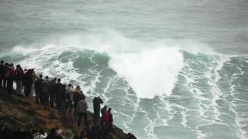 Wave watching on the rocky mountain of Nazare, Portugal - slowmo video