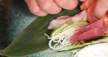 chef de sushi arreglando el filete de salmón fresco y atún con lima, pepino y rábano triturado. - tiro de ángulo alto video