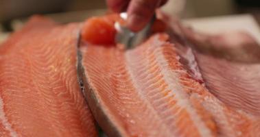 Retire el exceso de carne sobre el salmón crudo raspando con una cuchara. - tiro de ángulo alto video