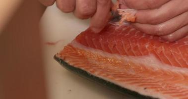 retirer les arêtes d'une viande de saumon non cuite à l'aide d'une pince à épiler. - prise de vue en plongée video