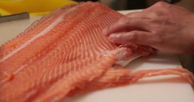 rebanar carne de salmón fresco con un cuchillo afilado para sushi - cierre, cámara lenta