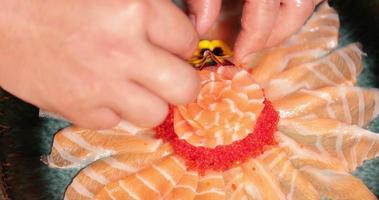 placage de nourriture - chef avec mise de fleurs fraîches sur une rose de saumon sashimi. - prise de vue en plongée