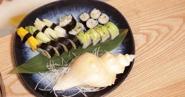 juego de sushi japonés recién hecho en un plato decorado con conchas marinas - bandeja de tiro de ángulo alto a la derecha video