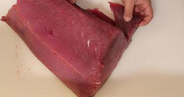 rebanar atún fresco y saludable con un cuchillo de carnicero. - primer plano de arriba hacia abajo video