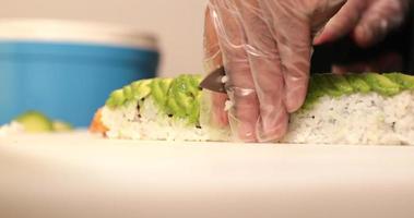 rebanar un delicioso y saludable rollo de sushi con aguacate maduro y camarones fritos - primer plano video