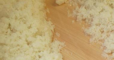 Mischen von japanischem weißem Reis, der mit Essigmischung angefeuchtet ist, in das Holzbecken in der Küche. - Hochwinkelaufnahme video