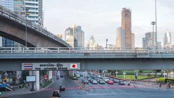 bangkok, tailandia - 1 de enero de 2023. timelapse 4k de tráfico de motos y semáforos de automóviles en el puente japonés tailandés. con fondo bts densos edificios de gran altura en la ciudad capital video