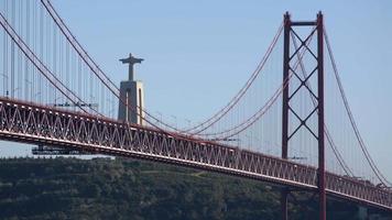 la gran y hermosa estatua de jesucristo junto al puente colgante de abril en portugal - plano general video