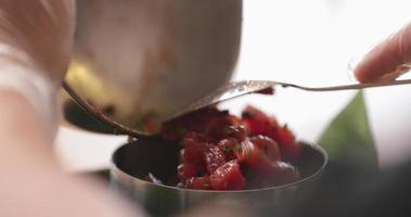 transfiriendo el ceviche de atún con cebolletas en un tazón de acero inoxidable más pequeño. - fotografía de cerca video