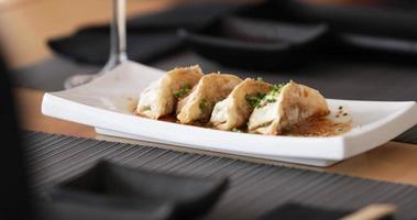 bord van gyoza knoedels geserveerd Aan de tafel. - langzaam beweging - pannen schot video