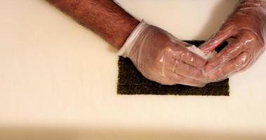 Chef With Disposable Gloves Spreading Japanese Rice On Nori Seaweed For Sushi Rolls.  - high angle shot video