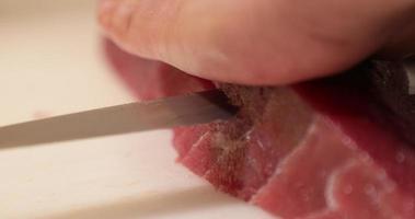 una persona cortando el filete de atún por la mitad con un cuchillo en una tabla de cortar. - fotografía de cerca video