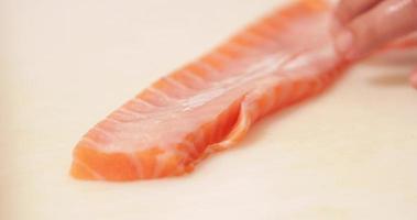 cortar carne de salmón con un cuchillo afilado - preparación de sushi - cerrar video