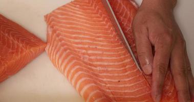 Cortar la carne del salmón por el centro y quitarle la piel. - tiro de ángulo alto video