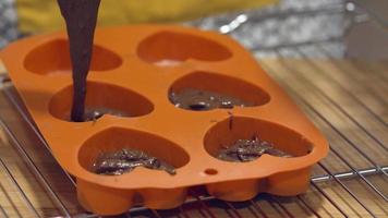 molde naranja en forma de corazón lleno de mezcla de chocolate - primer plano video