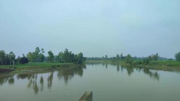 vista aérea de un río a la luz del día con cielo azul. dinajpur, bangladesh. video