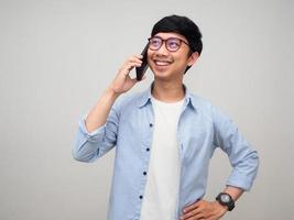 un hombre asiático positivo usa gafas y sonríe hablando con un teléfono móvil aislado foto