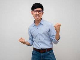 Asian businessman wear glasses blue shirt show fist up with satisfied happy successful isolated photo