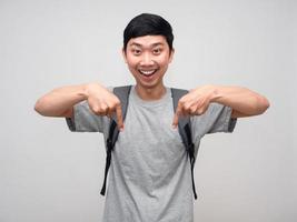 Positive man with school bag cheerful gesture point finger down photo